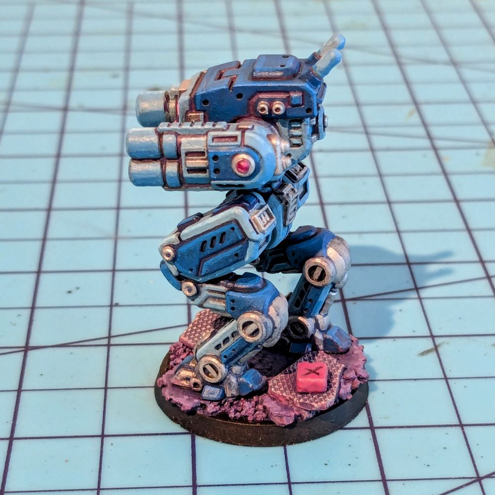 Side view of a small boxy robot miniature with cannons for arms and insect-like folding legs