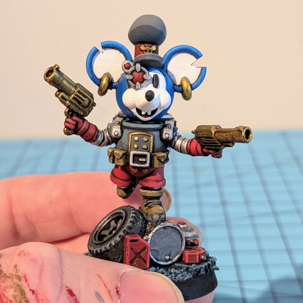 A cartoon rat miniature. It's wearing a spacesuit and has a robotic eye. The rat is jumping over some garbage 