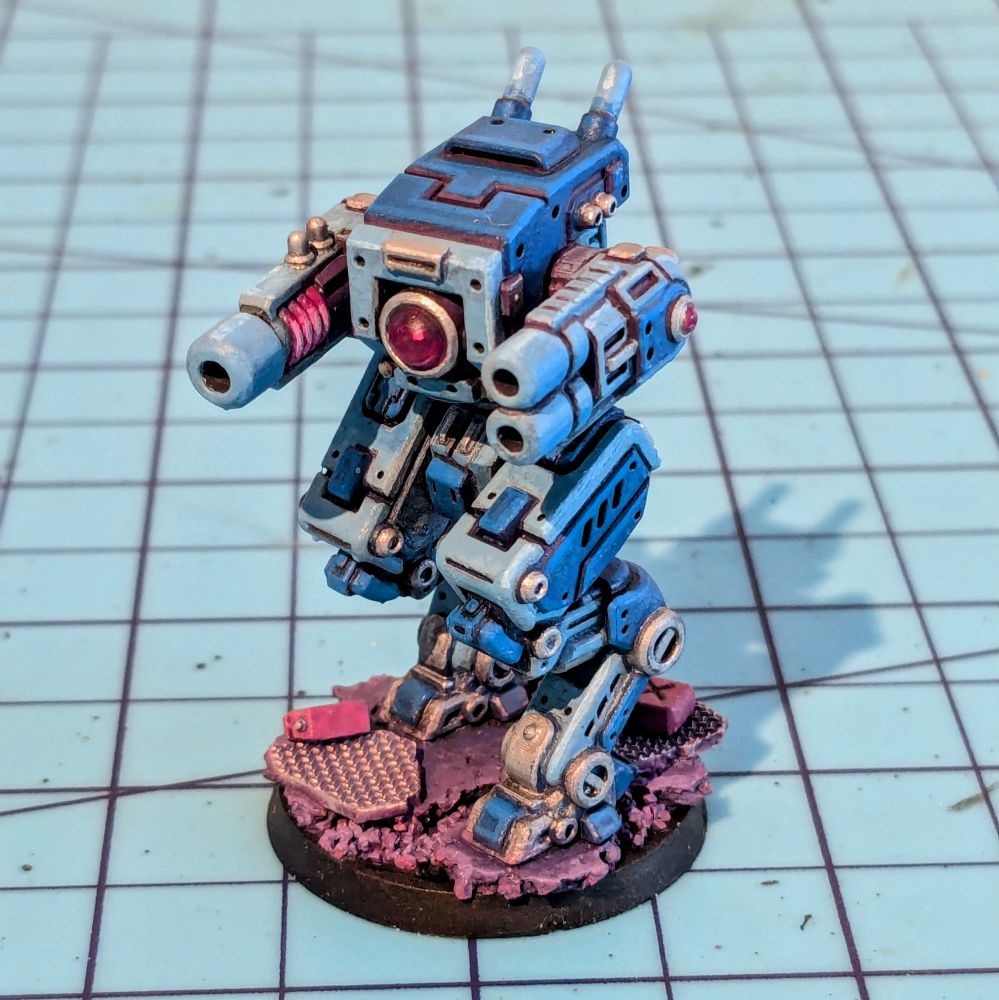 A small boxy robot miniature with cannons for arms and insect-like folding legs