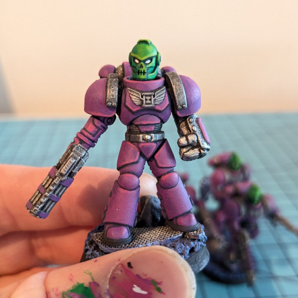 A scifi warrior tabletop miniature in power armor with a skull face helmet. 