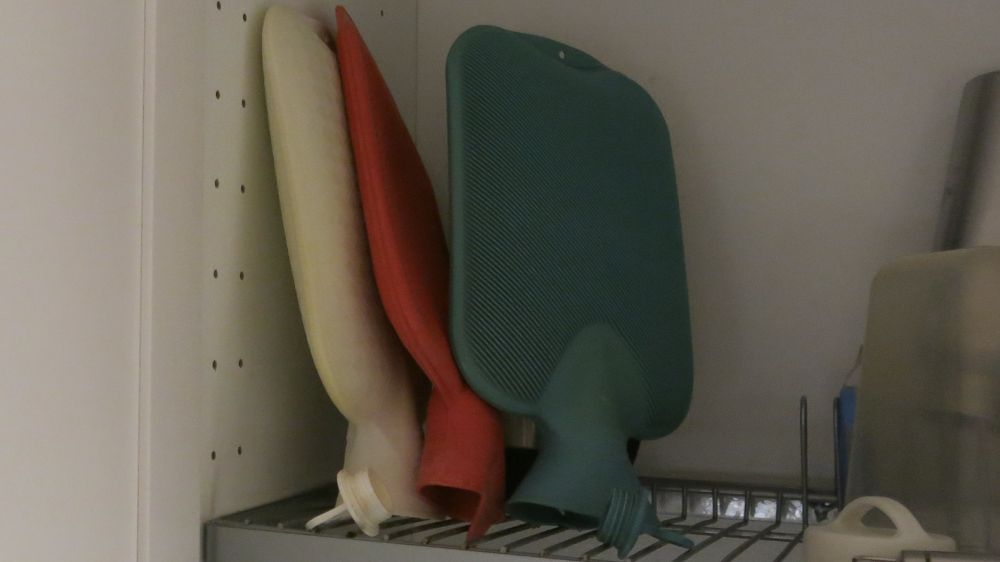 Drei Wärmeflaschen in den Farben Weiß, Rot und Blau wie die Fragezeichen im Logo der 3 ???