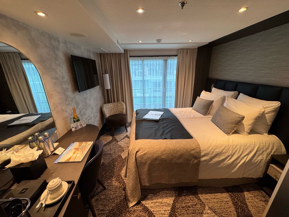 A Juliet balcony cabin showing a king-size bed and vanity desk area