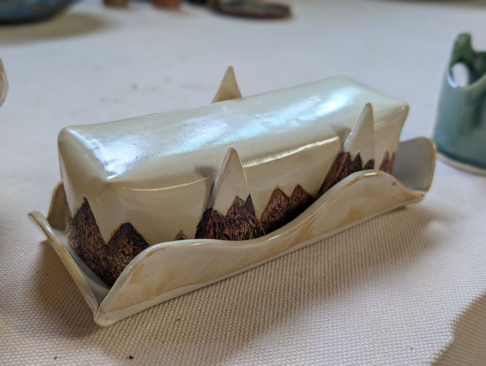 A ceramic butter dish with textured red-brown mountains and cream coloring elsewhere 