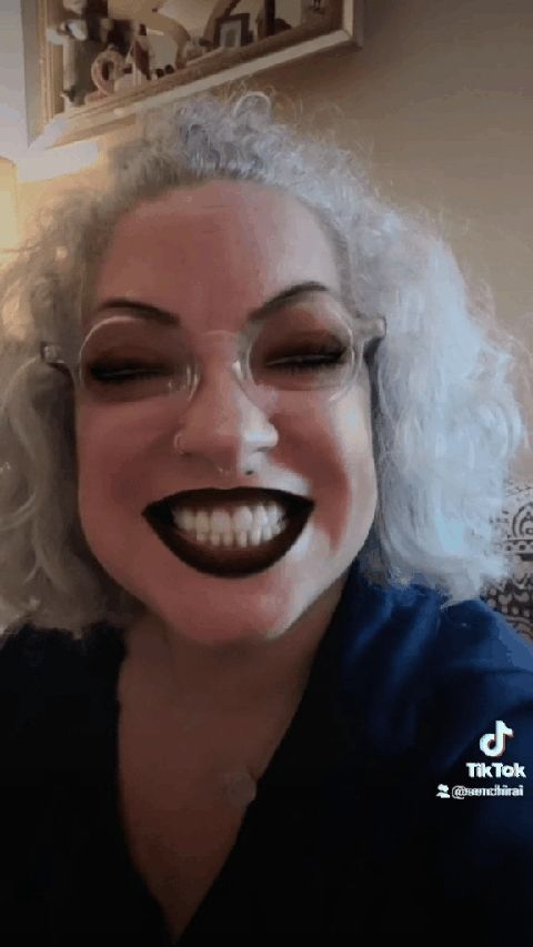 Grinning woman showing her teeth, unflinching eye contact