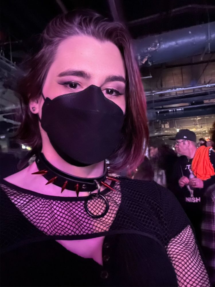 selfie of a woman in mask and club gear including a spiked collar