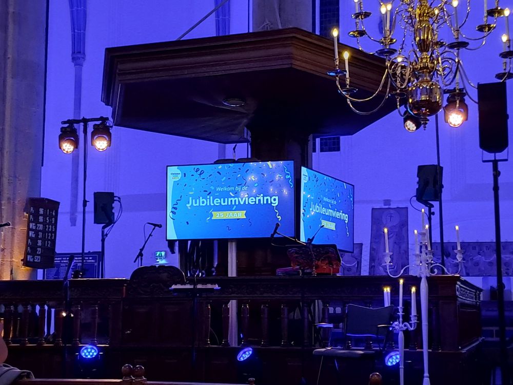 Preekstoel met ervoor een screen met de asnkondiging van de jubileumviering nsn de ChristenUnie 