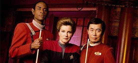 Captain Kathryn Janeway, flanked by "Ensign" Tuvok and Captain Hikaru Sulu (both garbed in Trek movie era "monster maroon" uniforms...), posing at the pool table in Voyager's holodeck recreation of Chez Sandrine's, a bar in France frequented by Tom Paris before he got lost in the Delta Quadrant.

Tuvok and Sulu are brandishing pool cues; I'm not gonna lie it actually looks like they're ready to give you a beating...