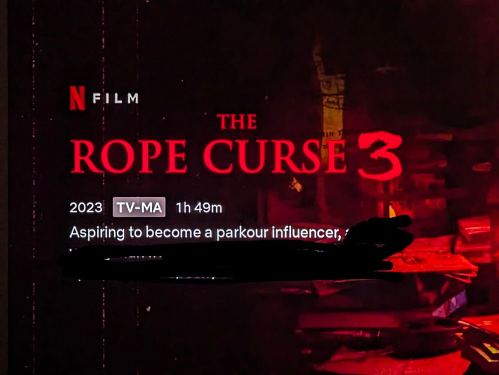 Netflix movie cover art for The Rope Curse 3. 2023, TV-MA, 1h 49m. The description reads "Aspiring to become a parkour influencer..." but the rest of it has been blacked out. Set over a dark red background featuring a photo of a table with stacks of money on it.