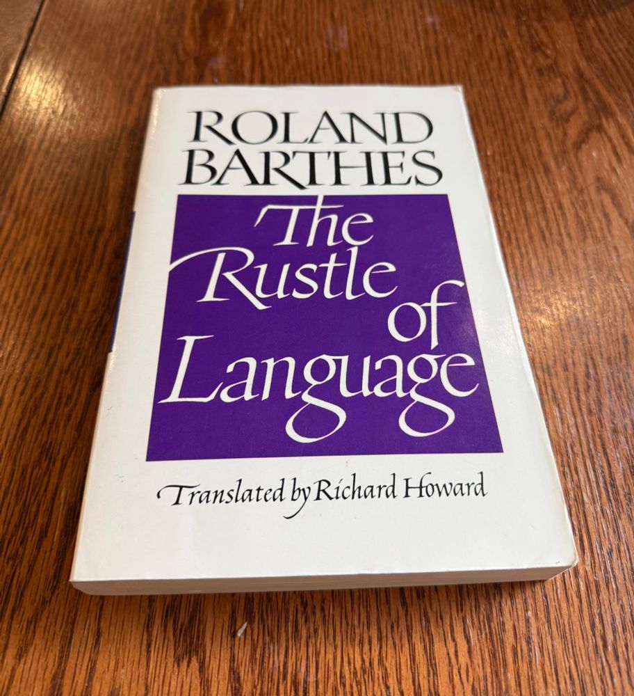 A copy of Roland Barthes's THE RUSTLE OF LANGUAGE on a wooden table. 
