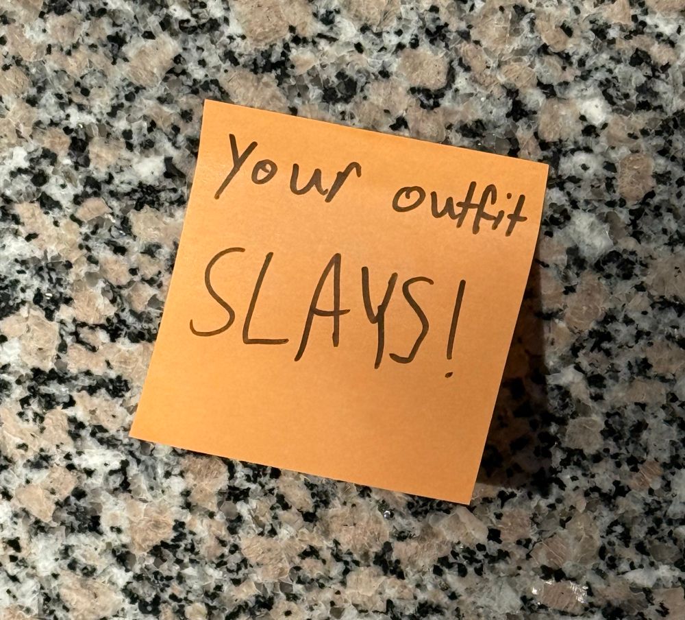 A post it that says your outfit slays stuck to some marble. 