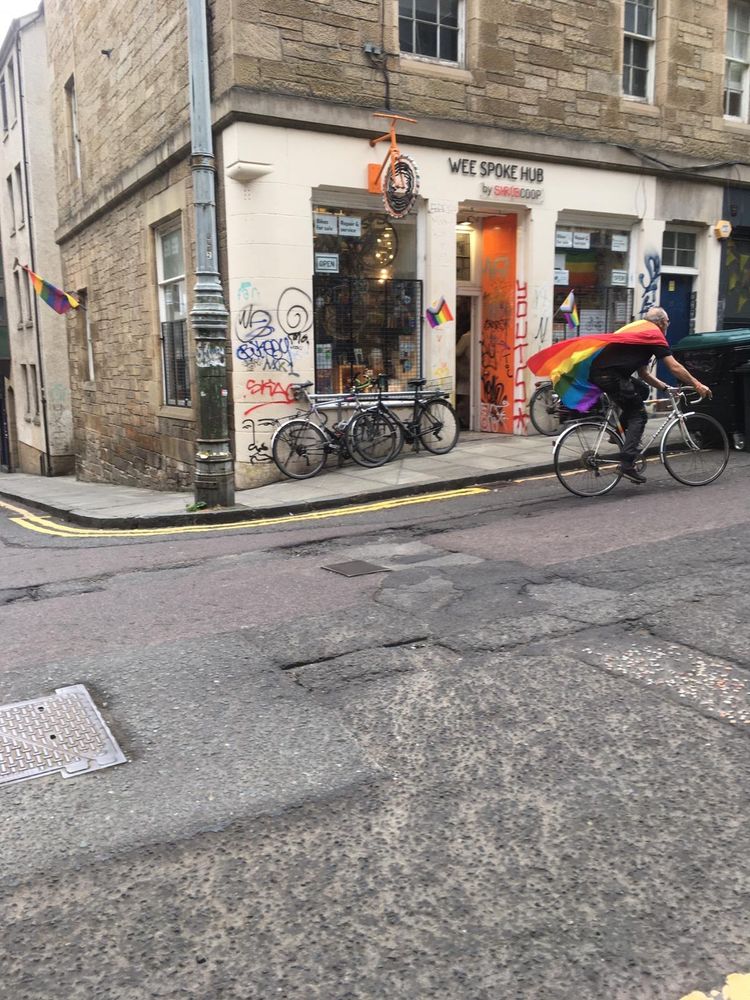 The same photo, one second later.  The cycle mechanic has now passed the front door of the Wee Spoke Hub, and is intently powering uphill.