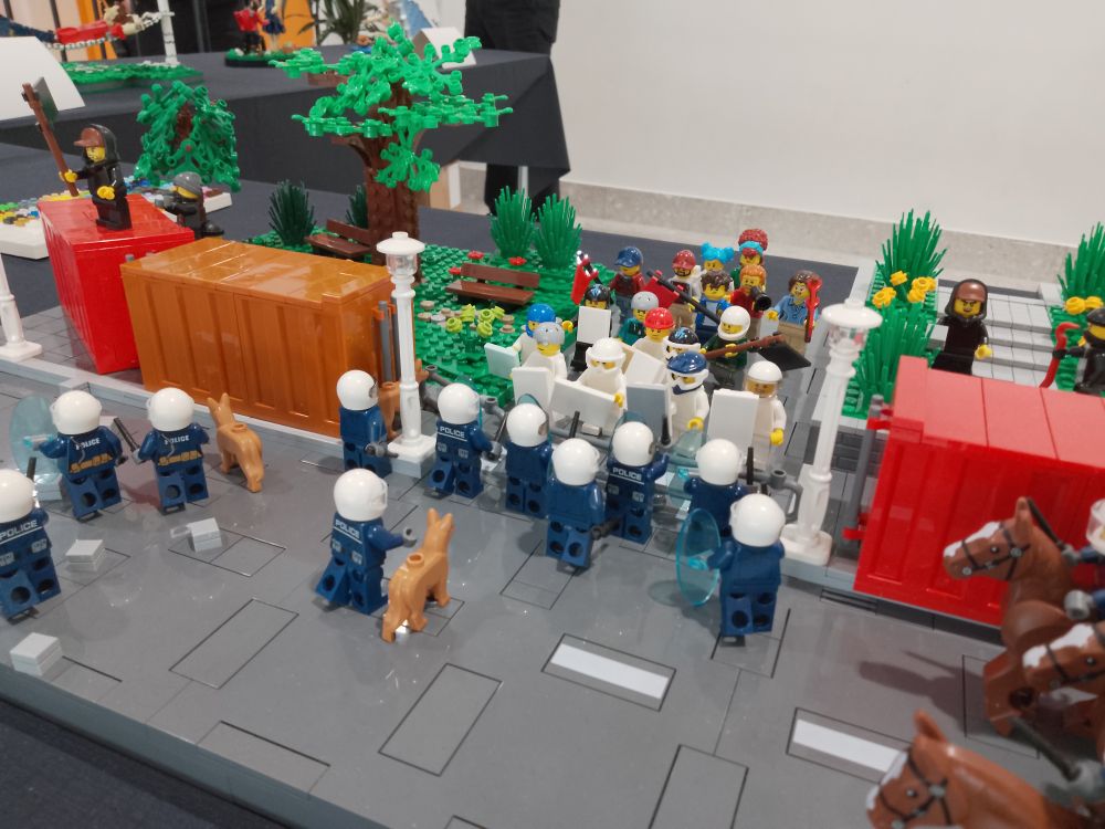 Legobygge av demonstranter som försöker bryta sig ut efter att ha blivit inspärrade på Hvitfeldtska gymnasiet med hjälp av containrar. I främre ledet de så kallade vita overallerna som är klädda i hjälmar och skyddsutrustning.