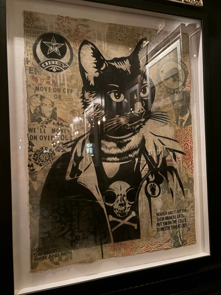 iconic piece of art from the Los Angeles restaurant The Black Cat, which shows a black domestic cat man with slogans from the Black Panther movement