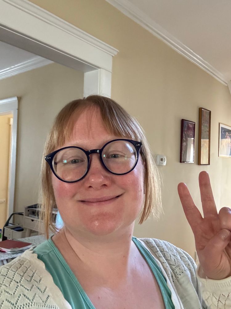 A person giving the peace sign in their home