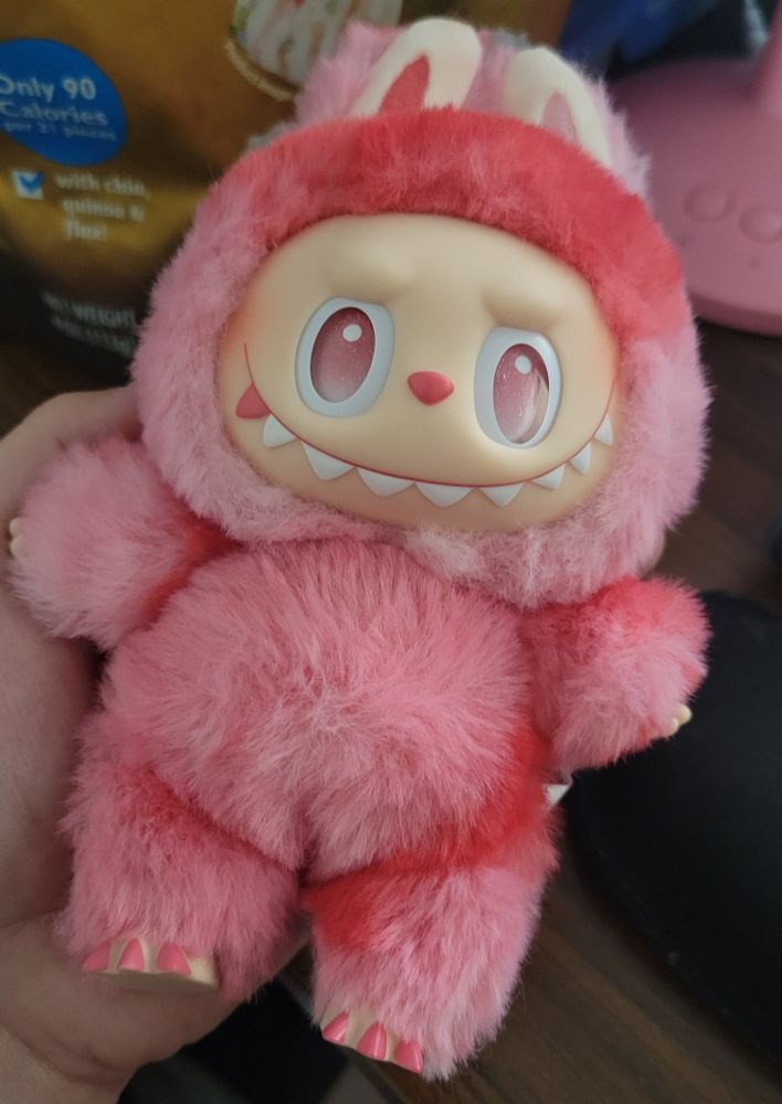 A picture of a plush pendant character called a Labubu. It is pink and red and named Love from the Big Into Energy series from The Monsters series.