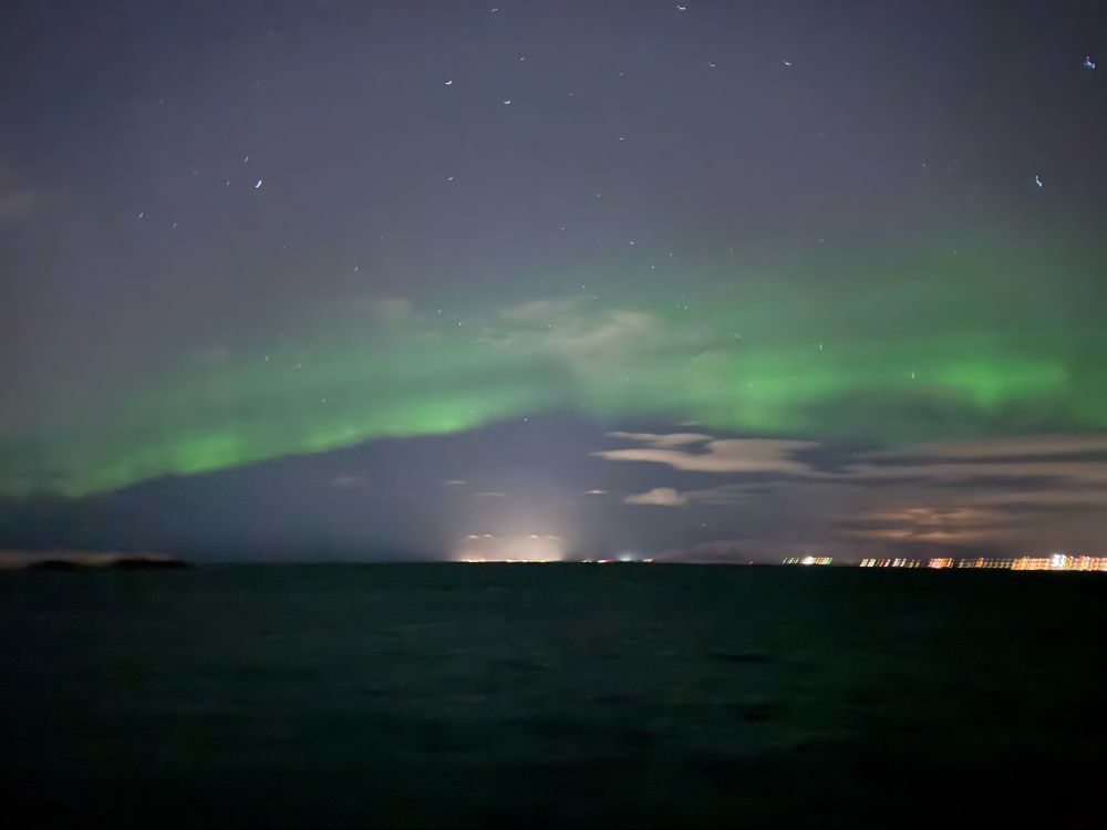 A band of green in the night sky over the dark ocean