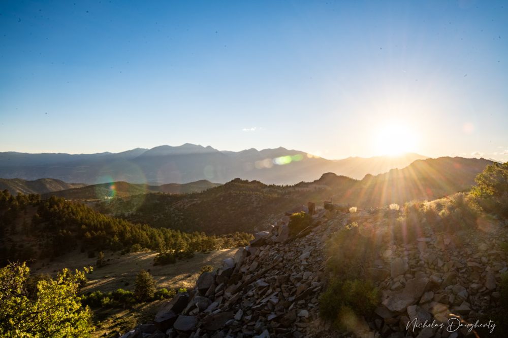 Layers of mountains and hills with a bright sunburst 
