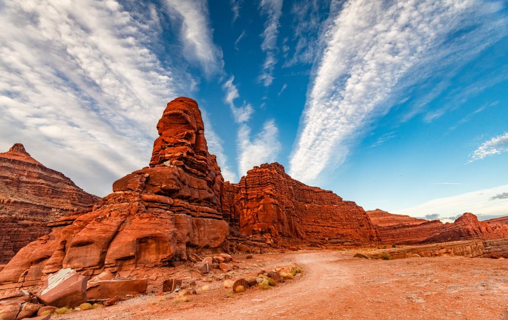Red rocks, a dusty road, and blue sky with clouds