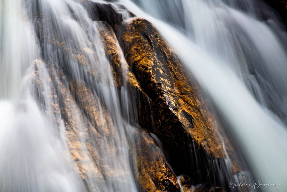 Long exposure of a waterfall over golden rocks