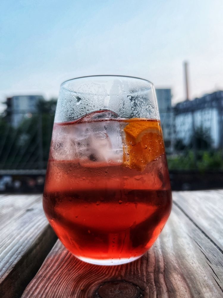 Ein Glas Spritz alkoholfrei auf einer Holzplanke, im Hintergrund die Spree.