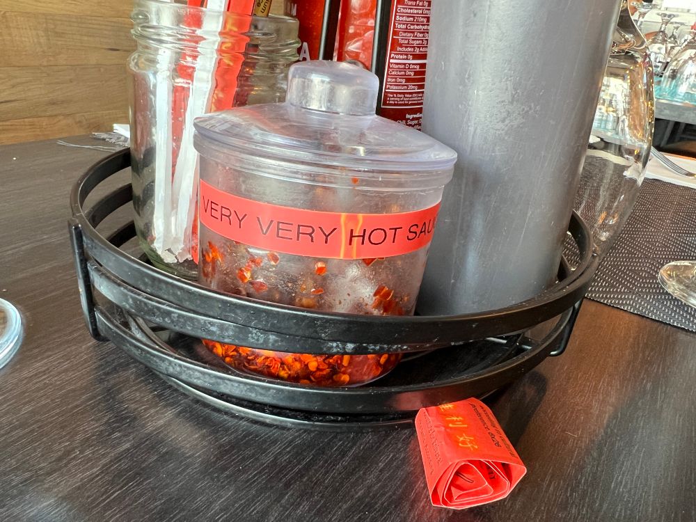 VERY VERY HOT SAUCE with condiments on a table.