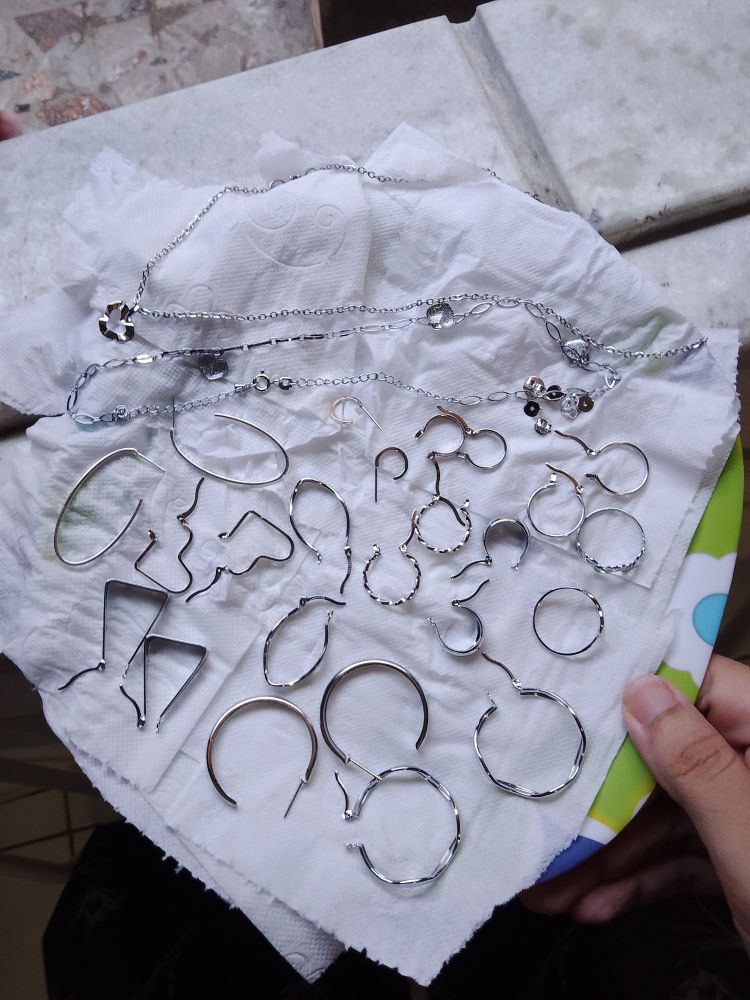 pares de argolas em aço e steel, e duas gargantilhas em aço e steel também, sob um prato forrado com papel higiênico