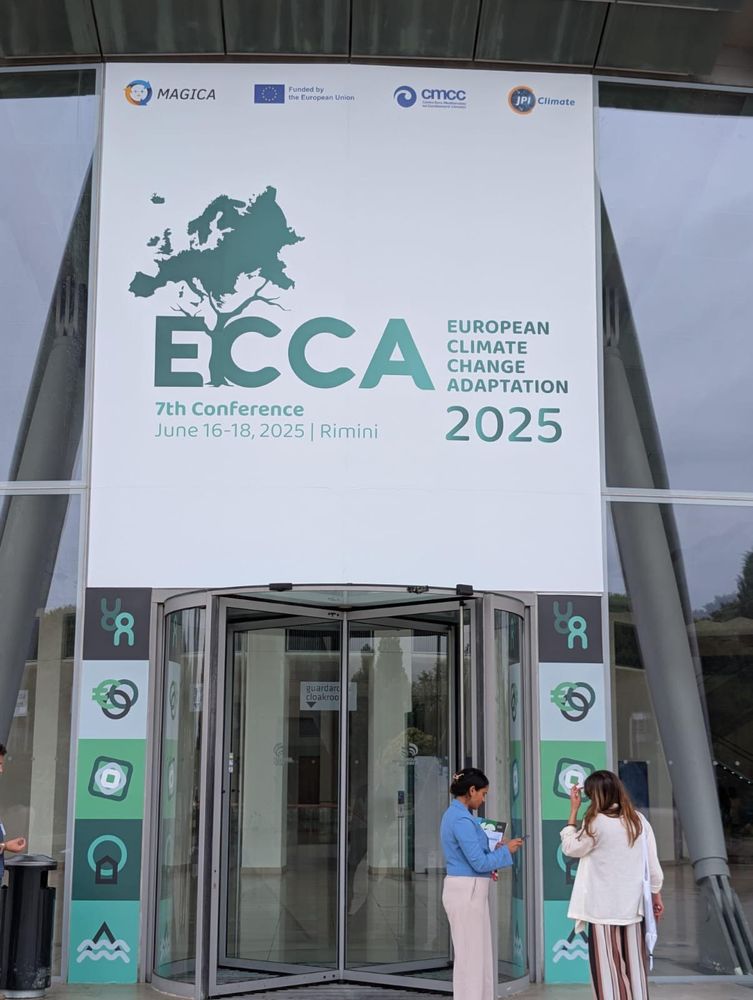 Two people standing in front of a sign advertising the ECCA conference