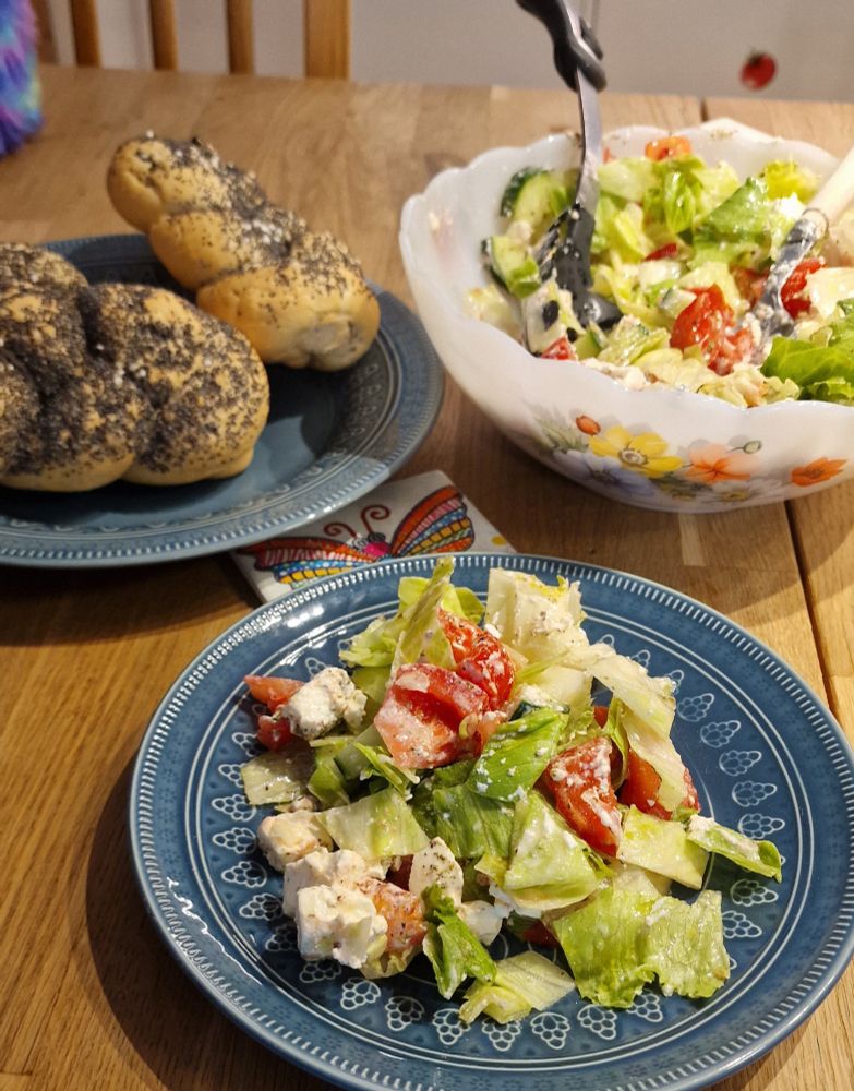 Griechischer Salat und Gebäck auf schönen blauen Tellern.