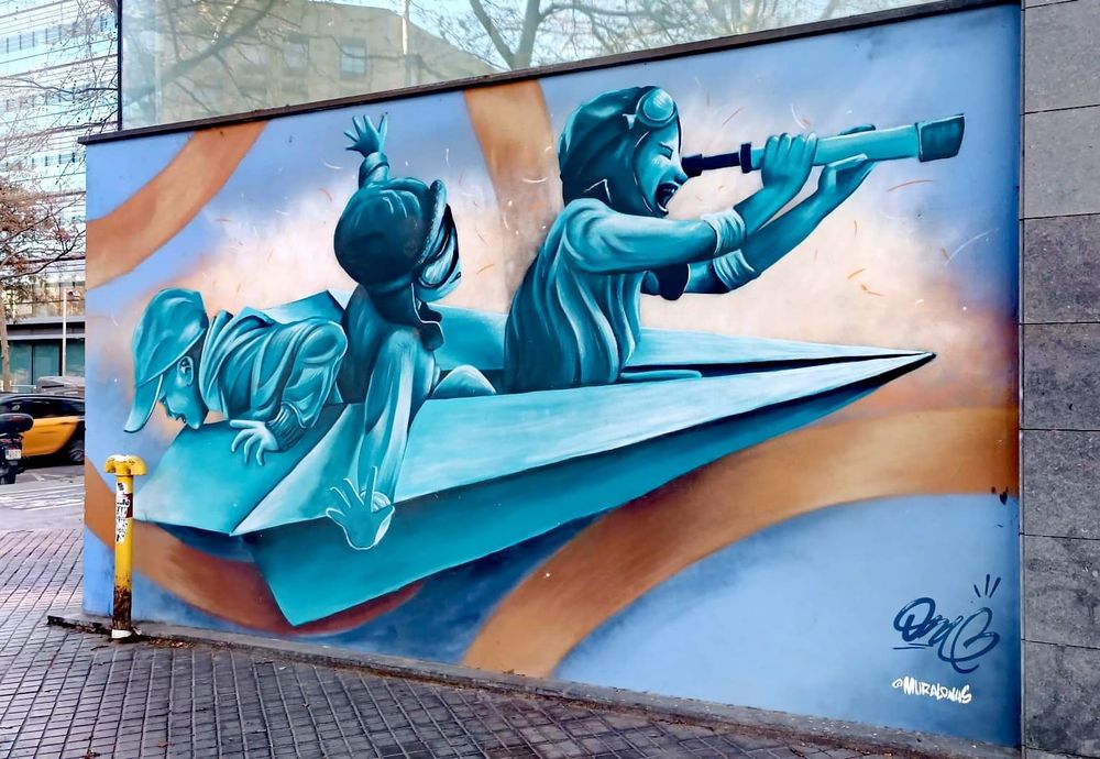 Ce street art est pein sur un mur. Il represente 3 enfants assis dans un pliage d'avion en papier. Le premier a un casque et des lunettes d'aviateur, il regarde au loin au travers d'une longue vue. Le deuxième personnage habillé pareil écarte les bras pour mimer le fait de voler. Le dernier porte une casquette, il est tourné vers l'arrière de l'avion et regarde quelque chose en bas