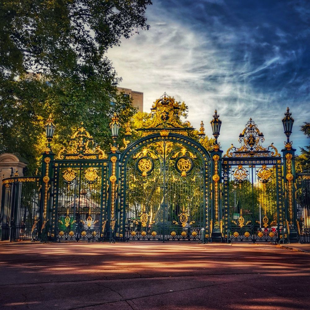 photo de la grille d'entrée du parc de la Tête d'Or à Lyon. Elle est en fer forgé, recouverte de feuille d'or, elle compte parmi les plus imposantes de France avec 32 m de long et 11 m de haut.