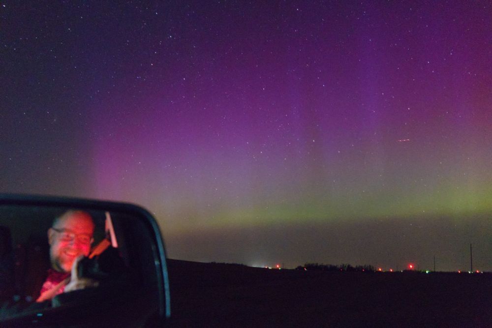 Self portrait with aurora using side mirror of car.