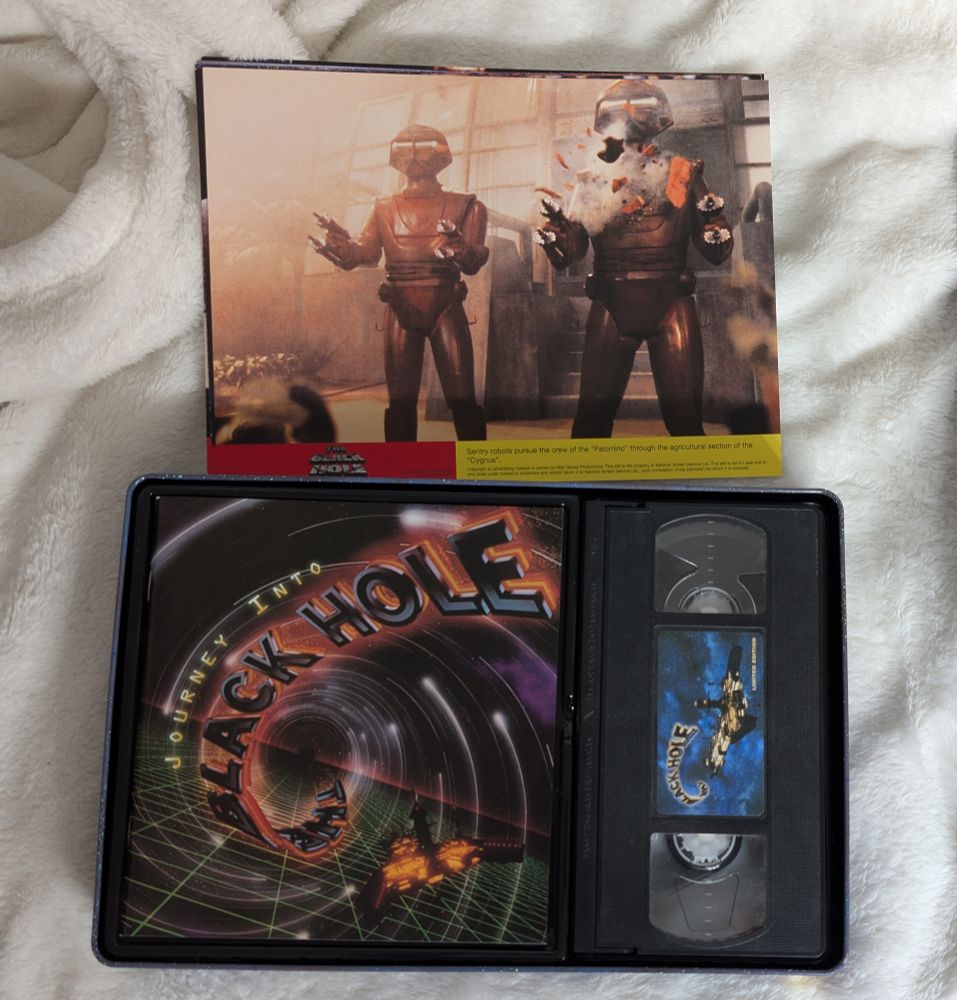 The inside of the tin with lobby cards, a VHS tape and Journey Into the Black Hole, which is about making the movie