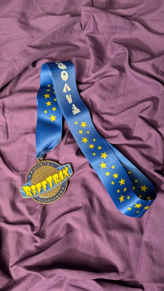 A medal with the Rifftrax logo on it. It says favorite customer on it