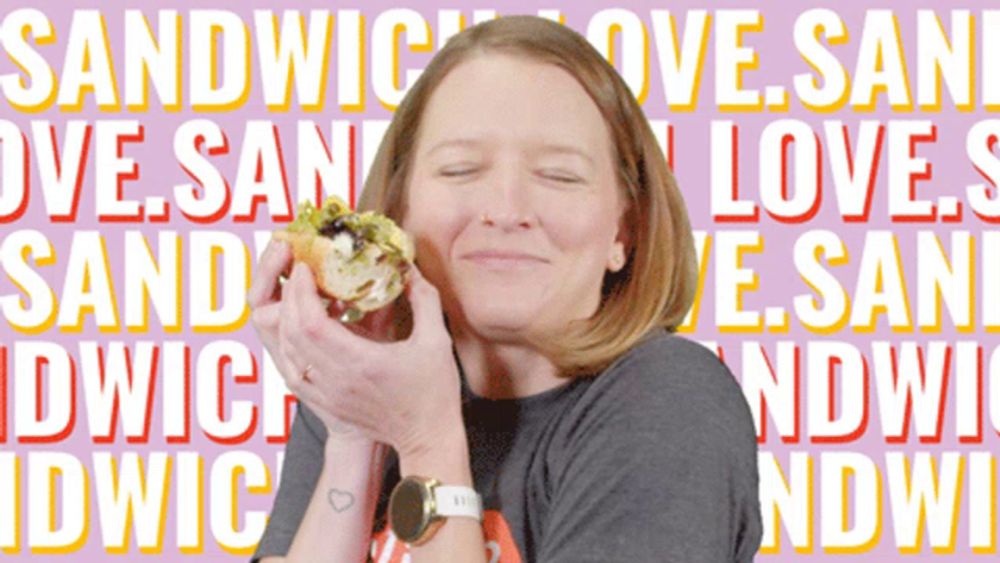 a woman is holding a sandwich in front of a background that says sandwich love san