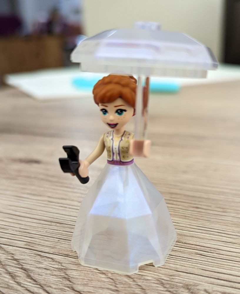 Tiny Lego figure with a pearlescent skirt and parasol, and a wrench in the other hand.