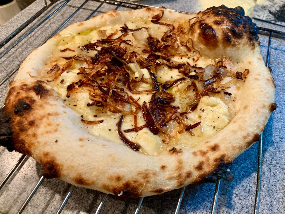 Neapolitan-style pizza with 4 types of cheese, black pepper, hot honey and fried onions for the crunch. Cooling on a rack 