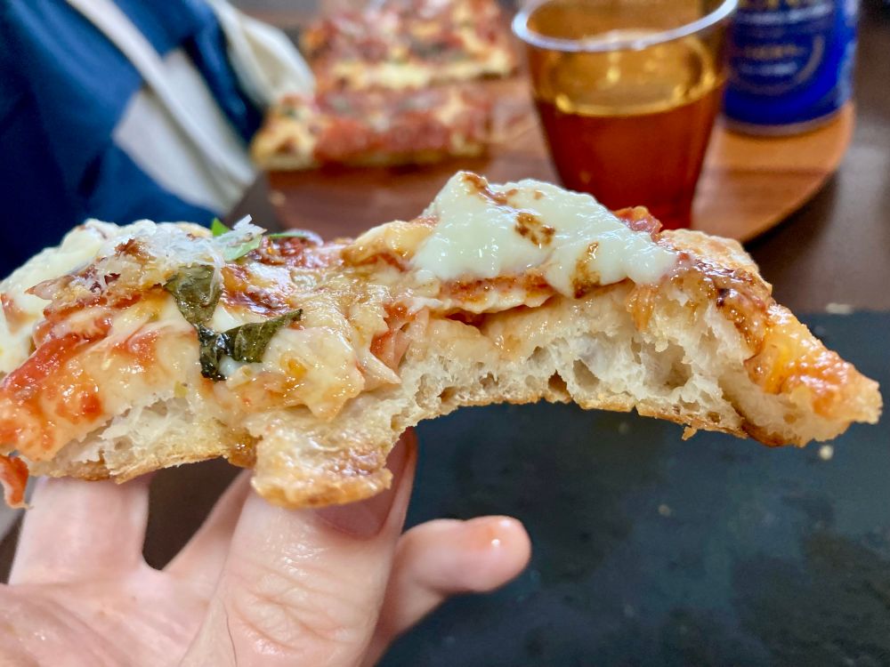 A chewed slice showing off the crisp but bubbly dough
