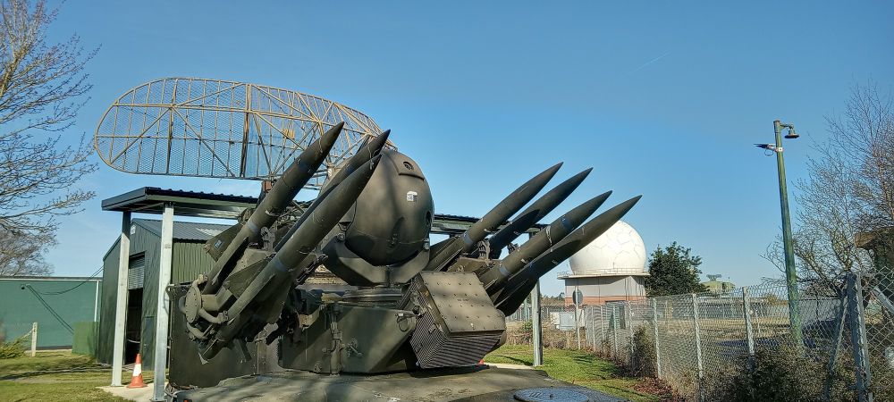 Photo, colour, exhibits at RAF Air Defence Radar Museum including Rapier missiles and T95 radar, white dome of operational RAF radar in the background.