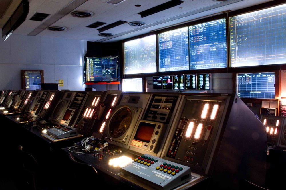 photo, colour, the Cold War Operations Room at the RAF Air Defence Radar Museum. The room is full of glowing radar consoles, lots of illuminated buttons and information boards. Headsets for the operators have been placed on the closest console.