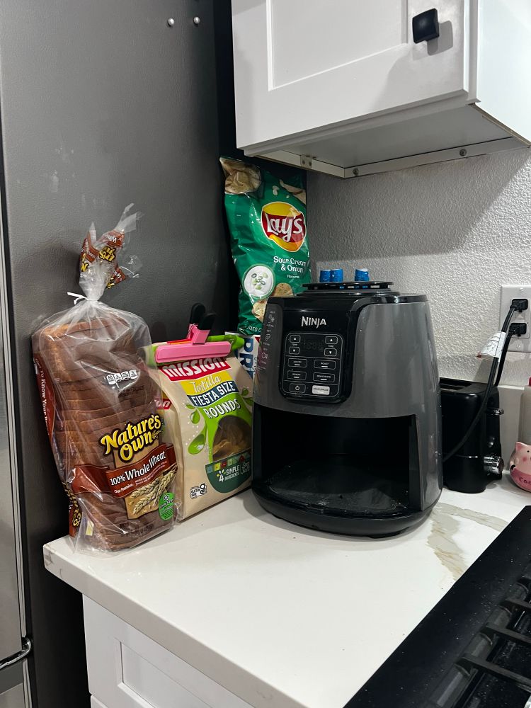 Chips bread and an airfryer with a toaster behind it. 