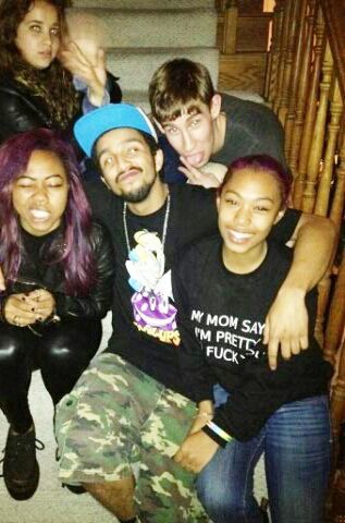 Micro at a party with four friends surrounding her. They are sitting on a staircase. Micro is sitting on the far left with long purple hair wearing all black. She is making a growling face with eyes closed. Another friend has his arms around both micro’s and another friends shoulders. Someone stands behind them sticking his tongue out at the camera. There is an orange, grainy instagram filter applied to the photo which gives it a classic 2014 look. 