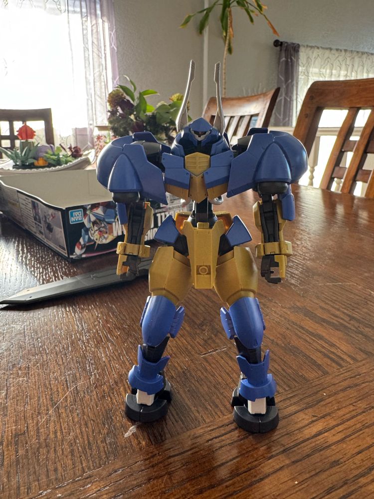 HG IBO Reincar, a Blue and Yellow Mobile suit. Broad shoulders, cloven feet, and horns give the illusion of a Minotaur