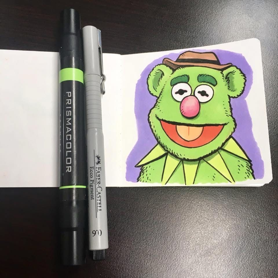 Small pen and ink and marker drawing of a hybrid of Kermit the Frog and Fozzie Bear. He has Fozzie’s basic body shape and hat but with green fur, Kermit eyes, and Kermit’s spiked collar. 