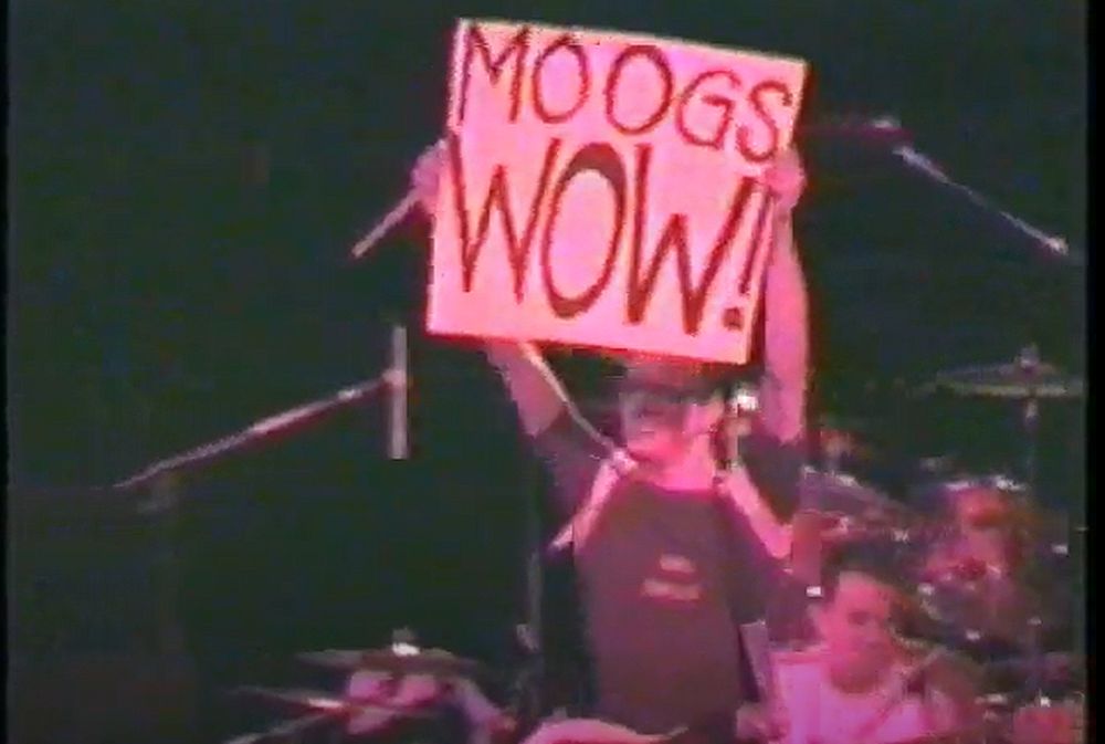 a guy holding up a sign that says moogs wow