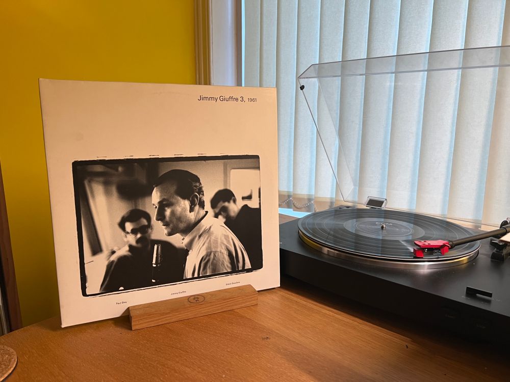 The cover of 1961 by Jimmy Giuffre 3 stands next to the turntable playing the LP