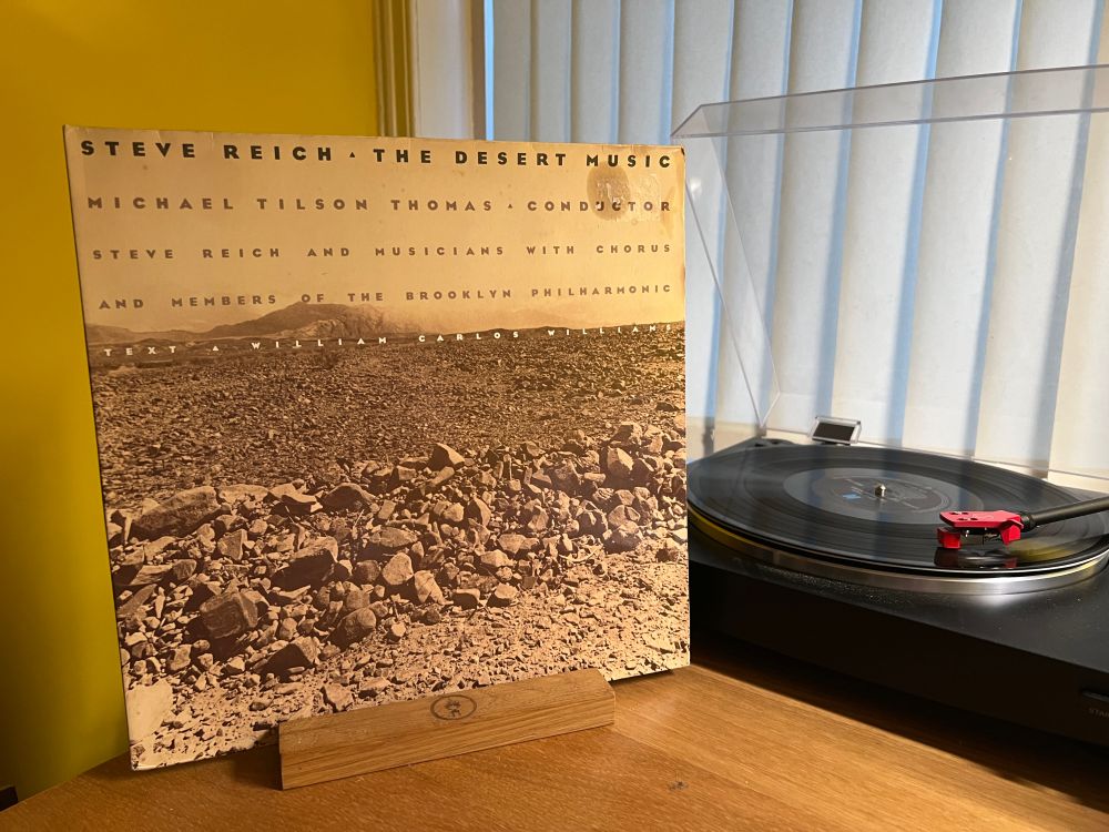 The cover of The Desert Music by Steve Reich stands next to the turntable playing the LP