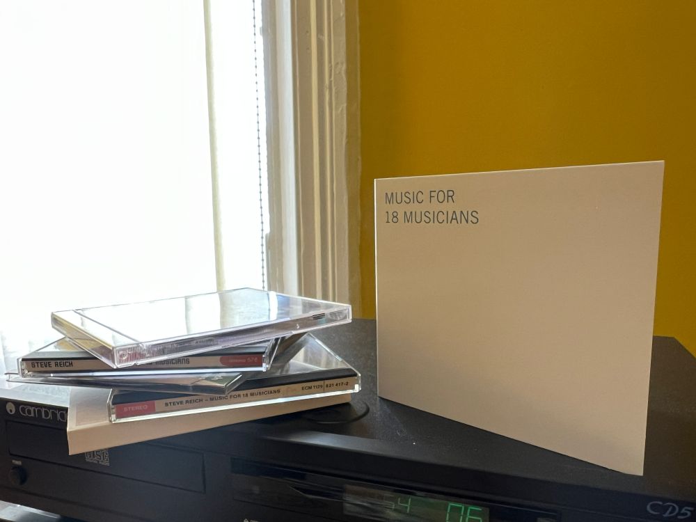 The cover of Music For 18 Musicians by Ensemble Modern stands next to four other CDs of the same piece