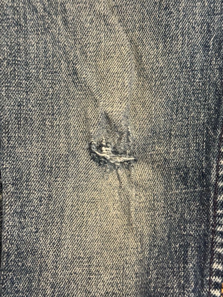 Photo of the knee of a pair of blue jeans with a hole in them