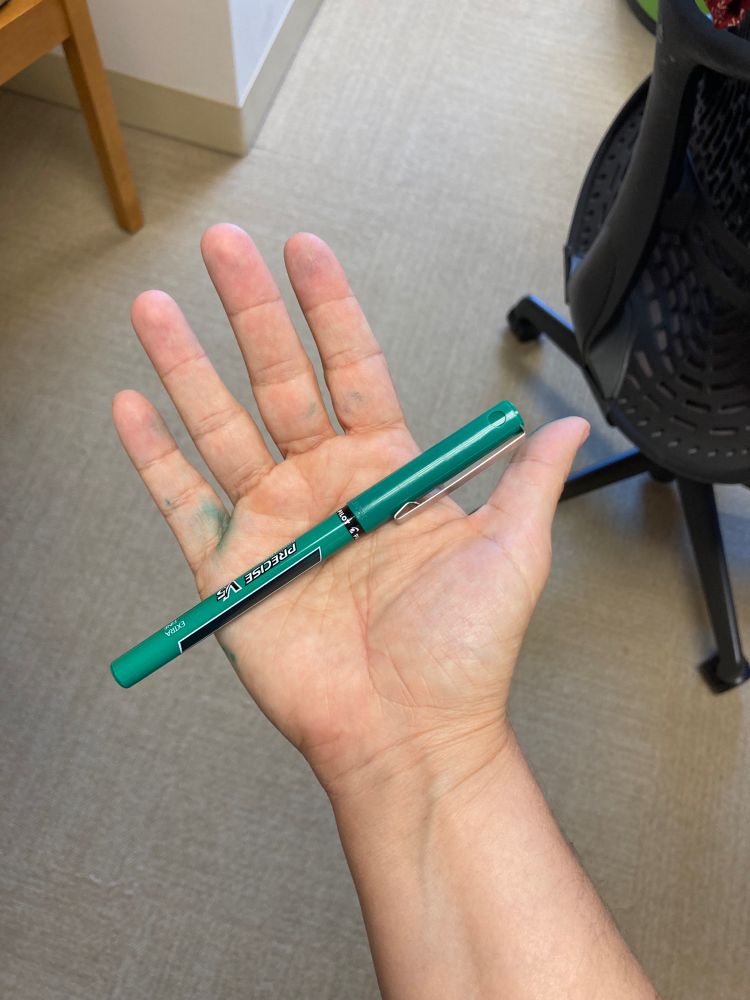 Green ink-stained hand holding a green pen. 