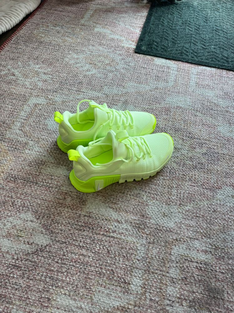 A pair of unworn hi-vis yellow/green Nike sneakers sitting on a dirty rug. There are not words to describe how highlighter bright these sneakers are and frankly even the photo doesn’t capture it. 